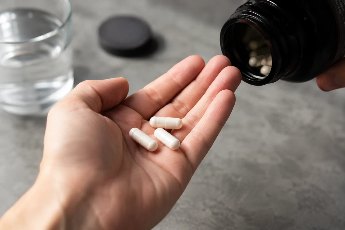 Gros plan sur un sachet de poudre de L-arginine versé dans une cuillère en bois